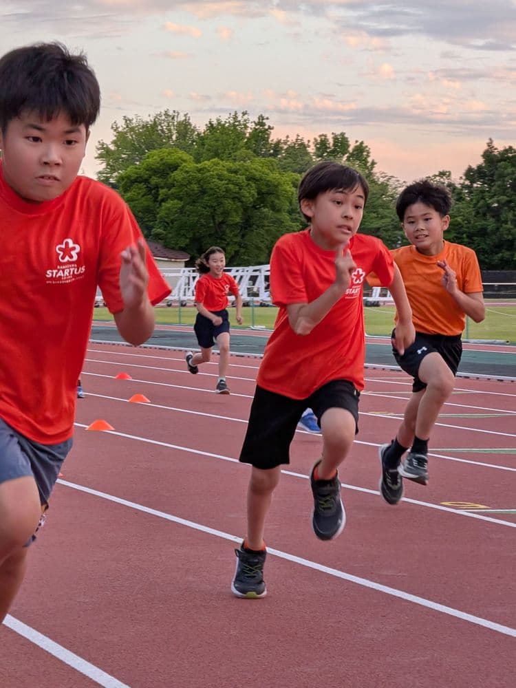 競技場のトラックを走る子どもたち